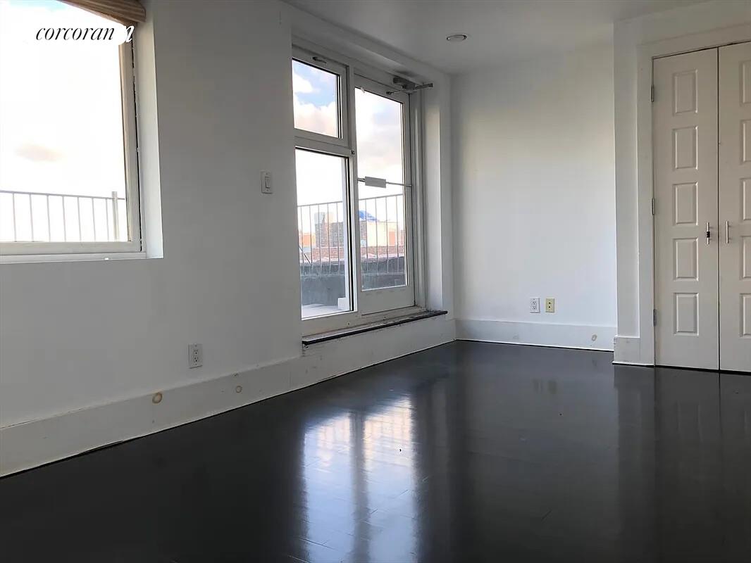 764 St Nicholas Avenue, Unit PH Manhattan, NY 10031 - Photo 7 of 14 an empty room with wooden floor and windows