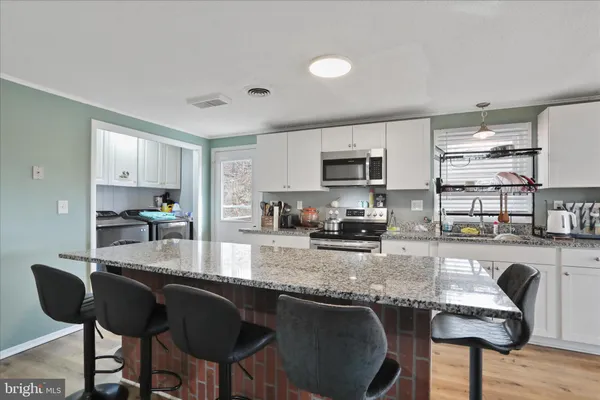 a kitchen with granite countertop kitchen island granite countertop a table chairs microwave and cabinets