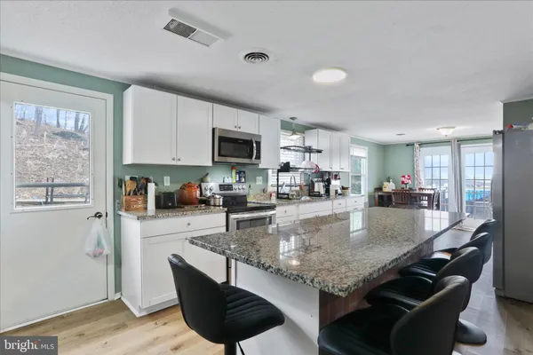 a kitchen with granite countertop stainless steel appliances a sink a counter top space cabinets and furniture