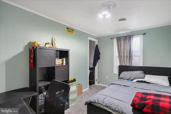a bedroom with a bed and dresser with wooden floor