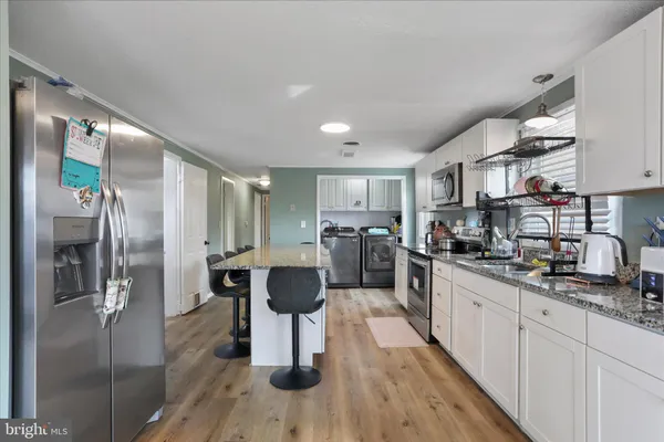 a kitchen with stainless steel appliances a refrigerator a stove a sink dishwasher and cabinets with wooden floor