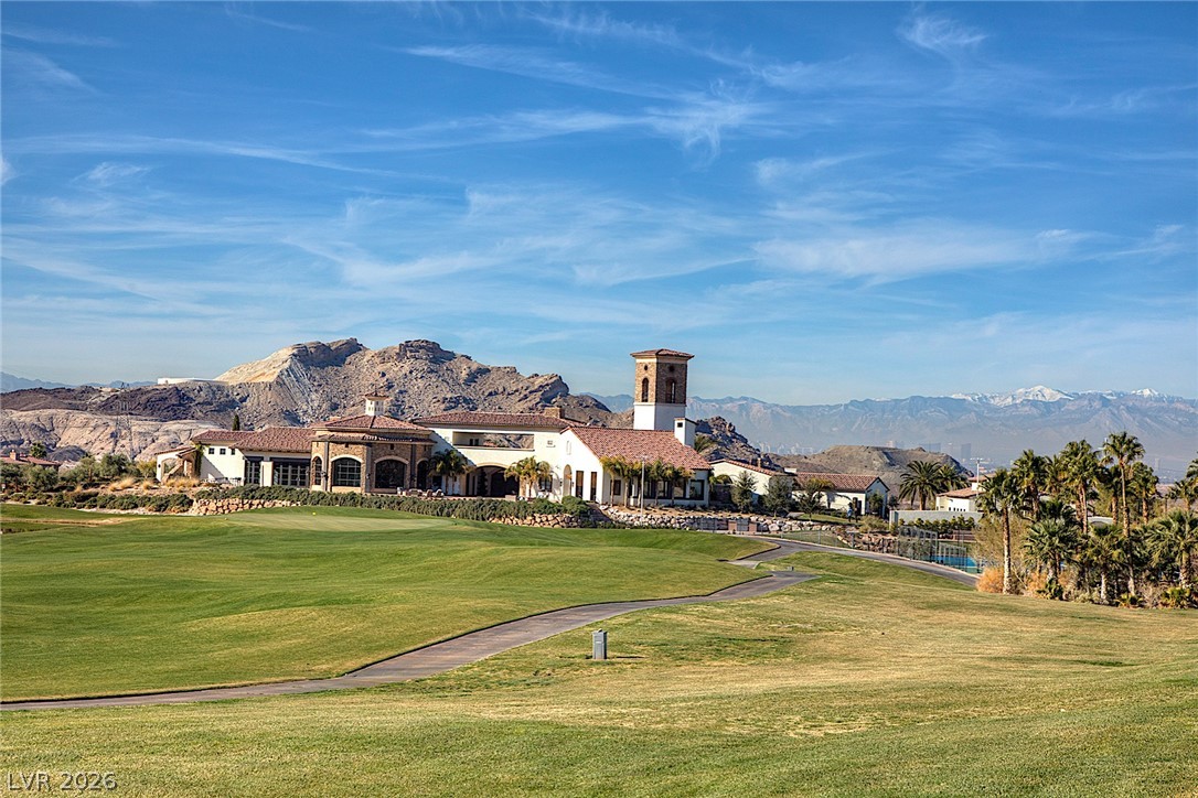 25 Falling Ridge Lane Henderson, NV 89011 - Photo 37 of 48 A Mediterranean-inspired clubhouse overlooks the verdant golf course, framed by rugged desert mountains and distant snow-capped peaks.