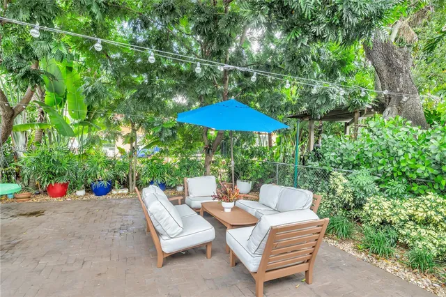 a backyard of a house with table and chairs under an umbrella