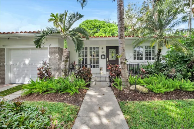 a front view of a house with a yard and potted plants