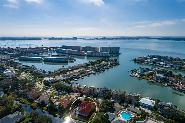 a view of a white house with a large pool and lawn chairs under an umbrella
