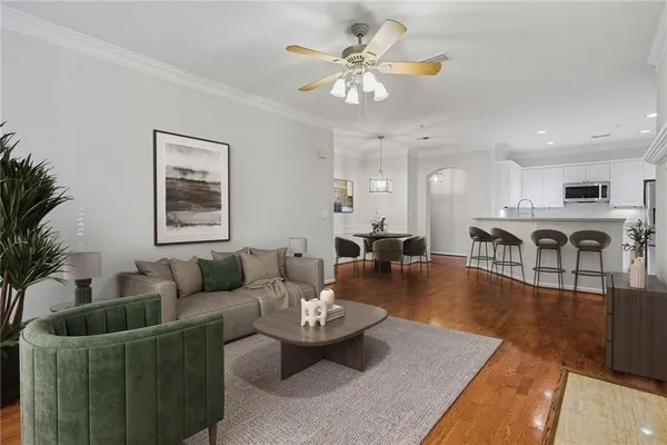 a living room with furniture kitchen view and a wooden floor