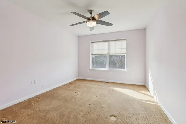 an empty room with a window and a ceiling fan
