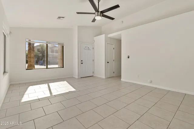 an empty room with windows and fan
