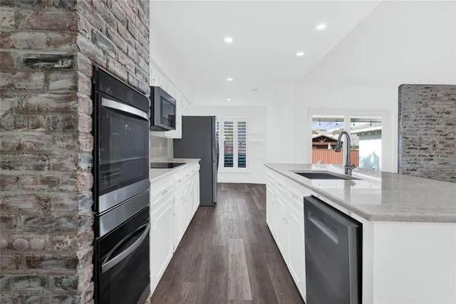 a kitchen with stainless steel appliances granite countertop a sink and a refrigerator