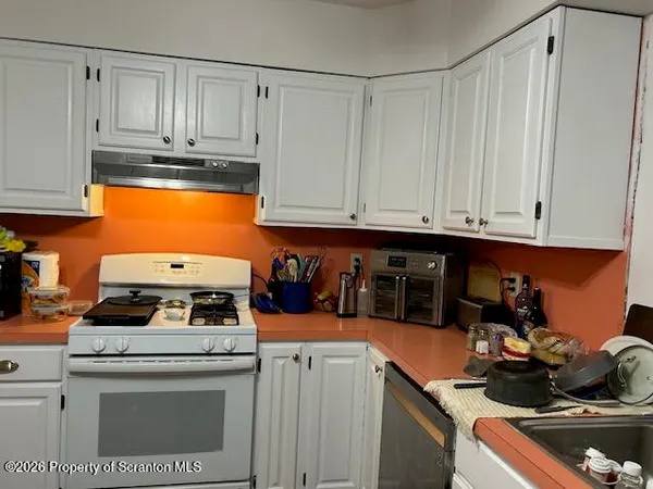 a kitchen with stainless steel appliances granite countertop a stove and a white cabinets