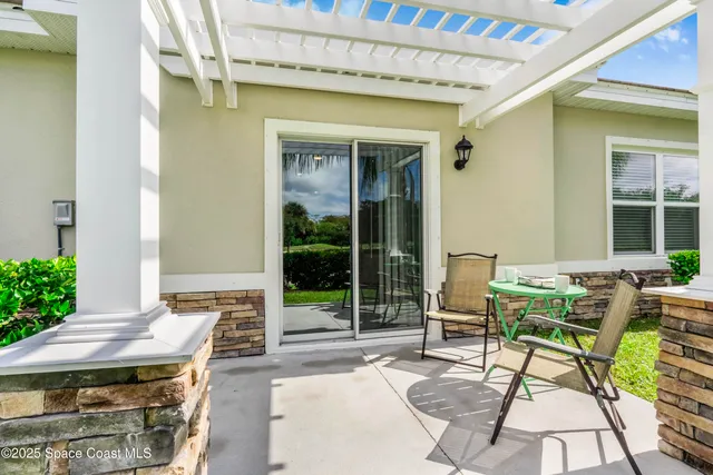 a patio with table and chairs and potted plants