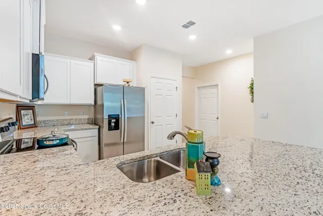 a kitchen with stainless steel appliances granite countertop a refrigerator a stove and a sink