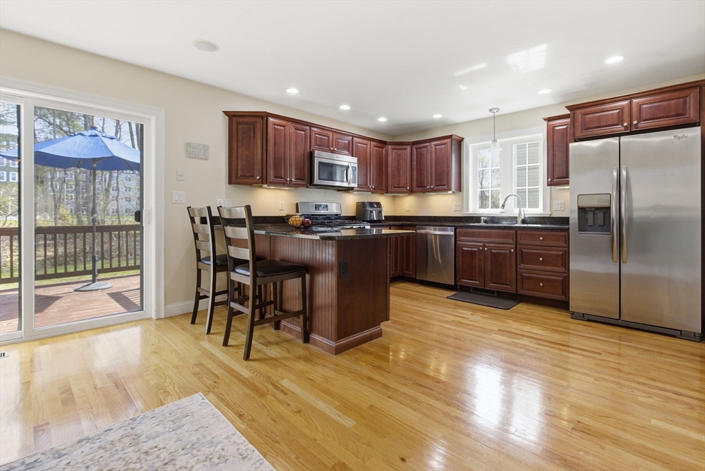 94 Progress Street, Unit 94 Abington, MA 02351 - Photo 5 of 35 a kitchen with stainless steel appliances granite countertop a stove top oven a sink dishwasher a dining table and chairs with wooden floor