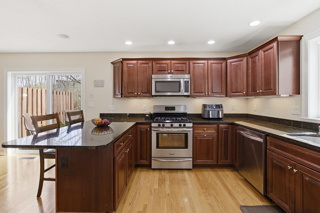 94 Progress Street, Unit 94 Abington, MA 02351 - Photo 6 of 35 a kitchen with stainless steel appliances granite countertop a stove a sink dishwasher and a microwave oven with cabinets