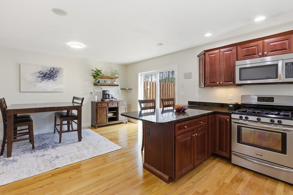 94 Progress Street, Unit 94 Abington, MA 02351 - Photo 9 of 35 a kitchen with stainless steel appliances granite countertop a stove top oven a sink dishwasher and cabinets with wooden floor