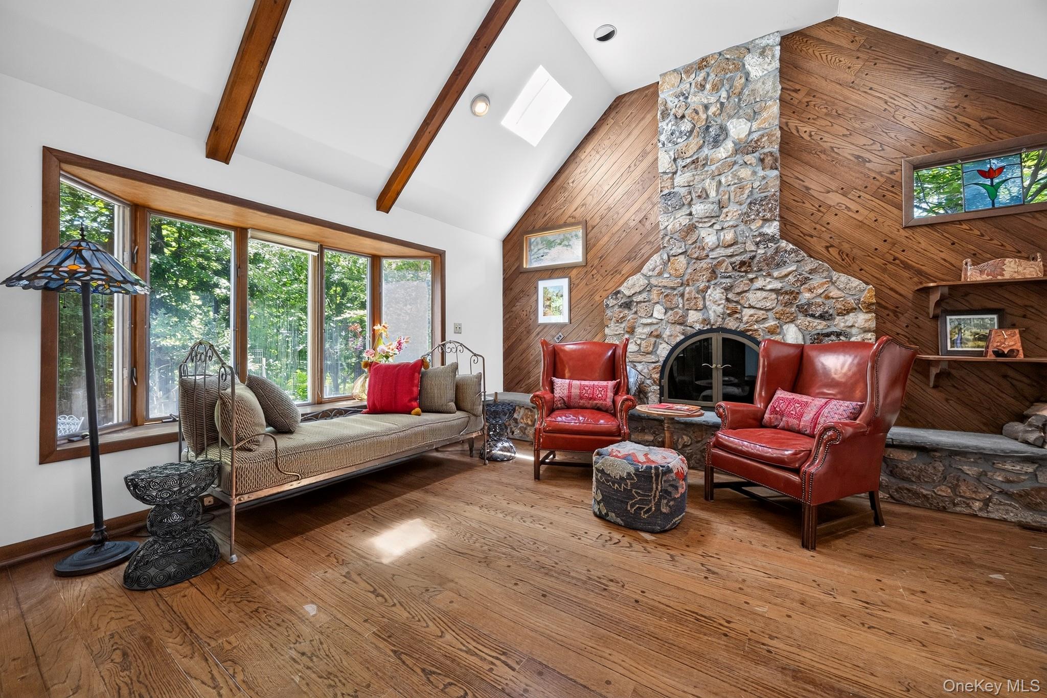 2 Terrace Road Suffern, NY 10901 - Photo 2 of 19 Vaulted ceiling with exposed wood beams, stone-clad fireplace, rich wood-finish flooring, bay window, and skylight