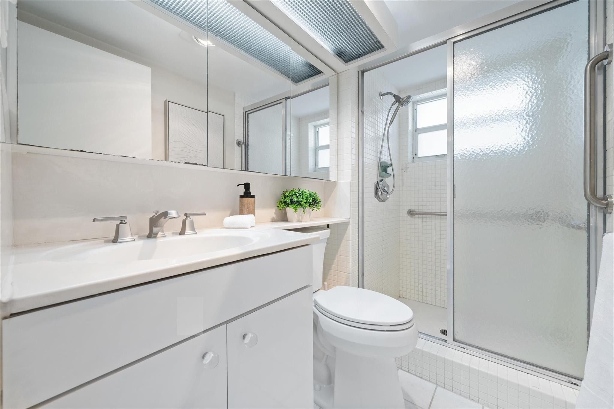 215 North Birch Road, Unit 2B Fort Lauderdale, FL 33304 - Photo 23 of 34 a bathroom with a shower sink vanity mirror and toilet