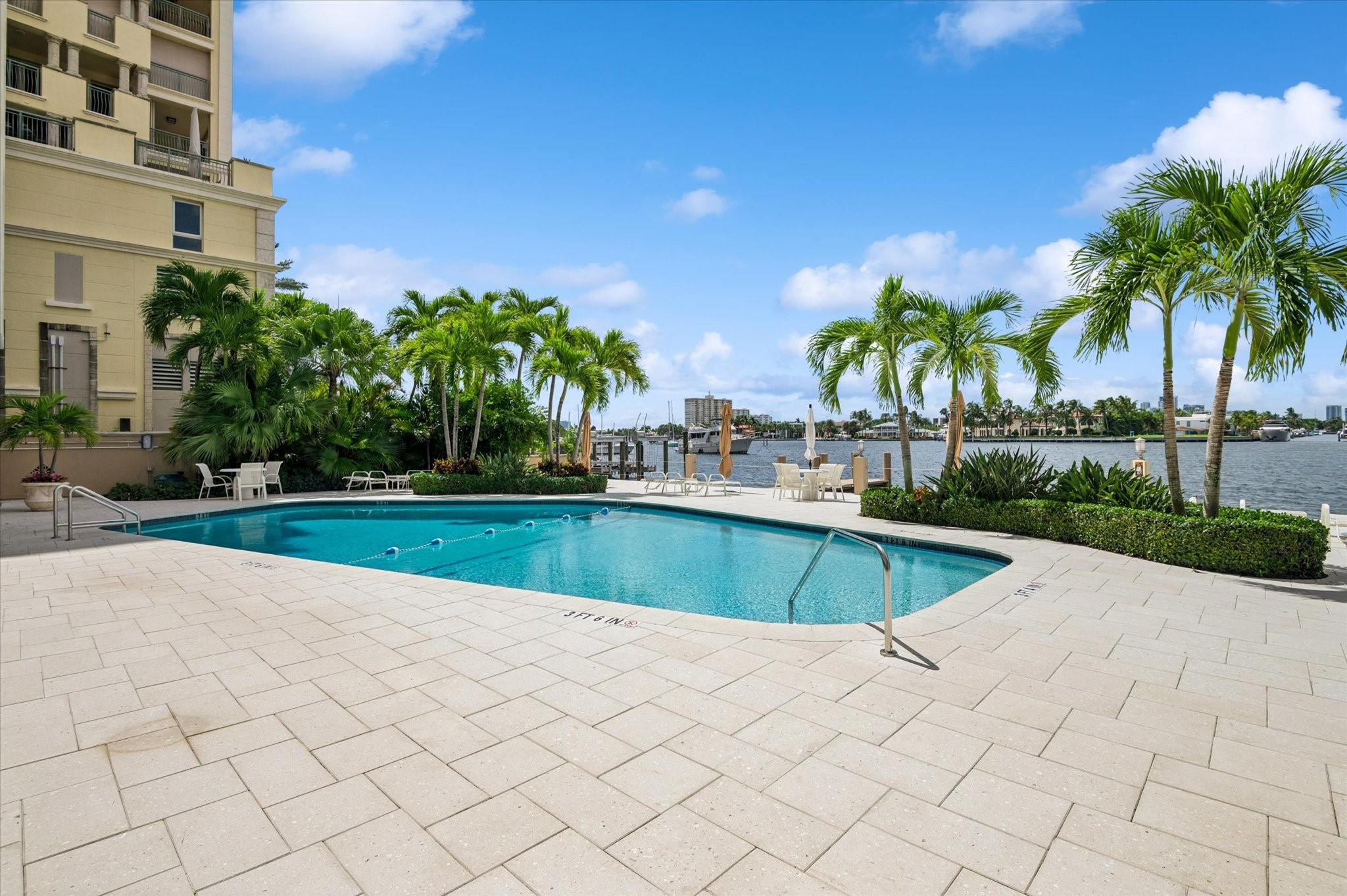 215 North Birch Road, Unit 2B Fort Lauderdale, FL 33304 - Photo 32 of 34 a view of a swimming pool with a lawn chairs and palm trees