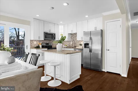 a kitchen with stainless steel appliances granite countertop a stove a refrigerator a kitchen island a table and chairs in it