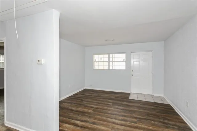 a view of an empty room with wooden floor and a window