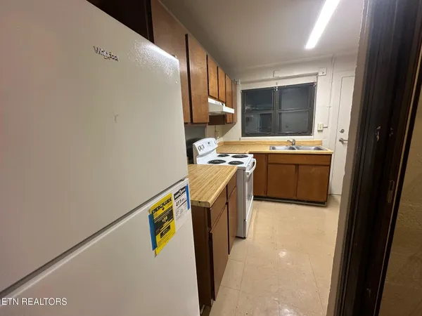 a view of kitchen with stainless steel appliances granite countertop refrigerator stove and a sink