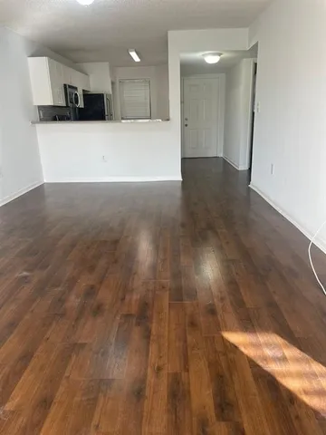 a view of kitchen and empty room with wooden floor