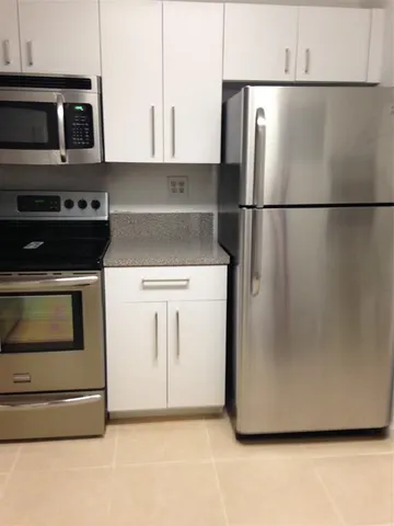 a kitchen with stainless steel appliances granite countertop a refrigerator a stove and a microwave