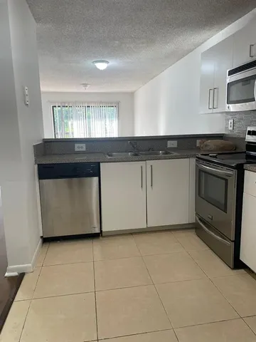 a kitchen with granite countertop a stove a sink and a microwave