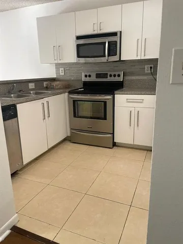 a kitchen with stainless steel appliances granite countertop a stove a microwave and a sink