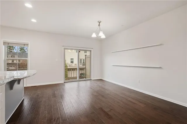 an empty room with wooden floor chandelier and windows