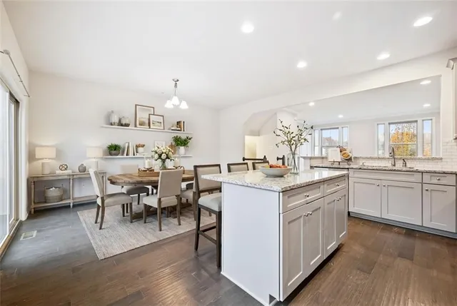 a kitchen with granite countertop a sink and white cabinets with wooden floor