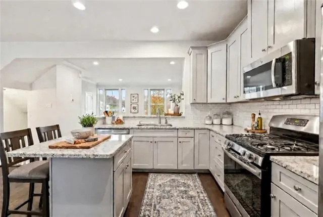 a kitchen with stainless steel appliances granite countertop a stove a sink and a microwave