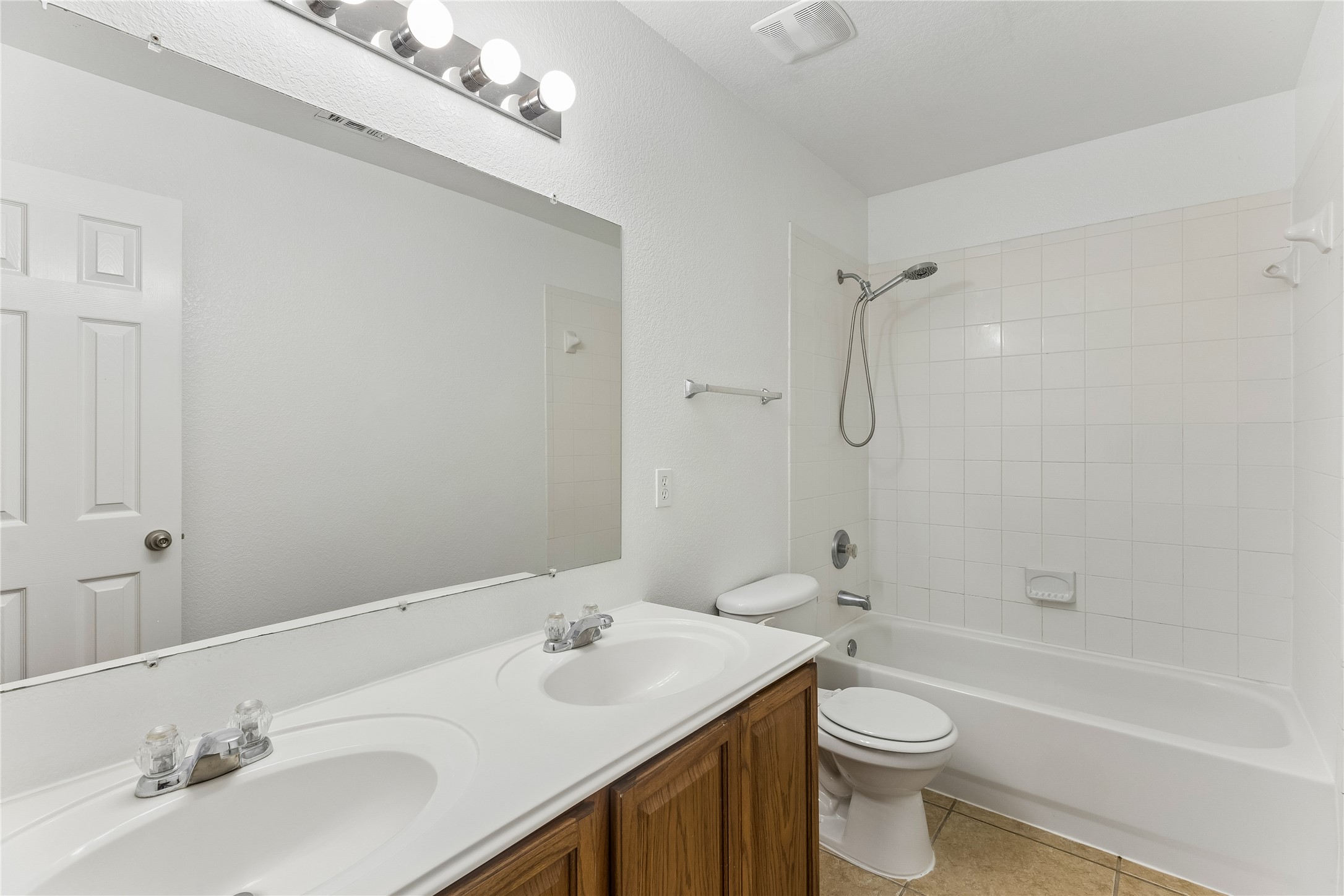 2372 Paradise Ridge Drive Round Rock, TX 78665 - Photo 34 of 40 Double vanity in a primary bathroom featuring a clean, white-tiled tub and shower combination.
