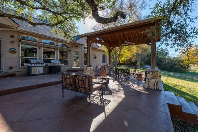 a view of a patio with dining table and chairs with a large tree