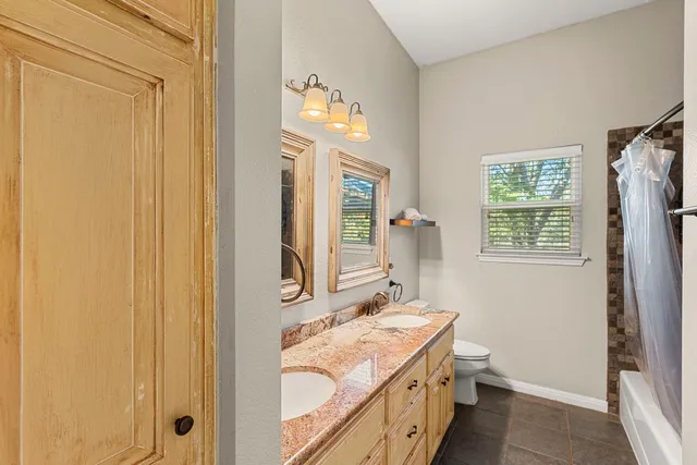 a bathroom with a granite countertop sink vanity mirror and a bathtub