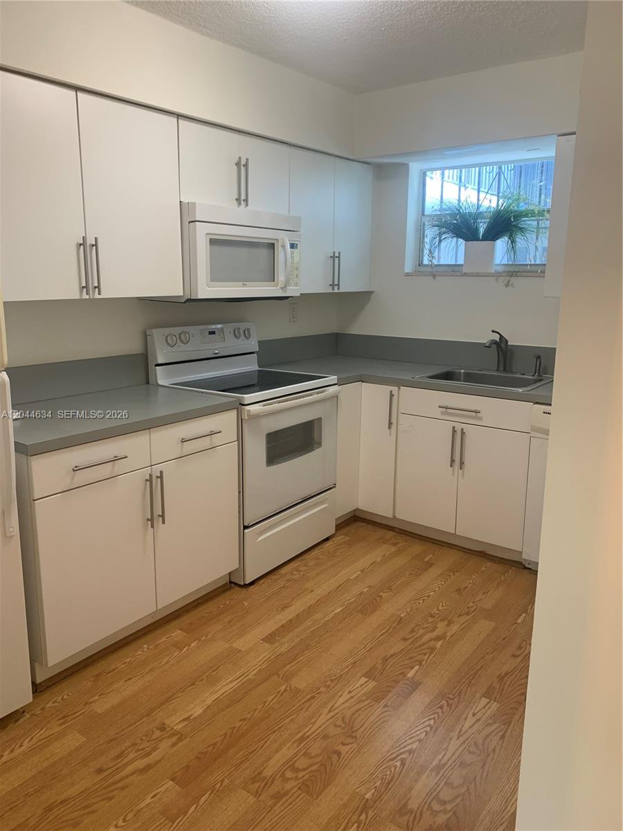 2460 Southwest 18th Avenue, Unit 1205 Miami, FL 33133 - Photo 10 of 21 a kitchen with granite countertop white cabinets and a sink
