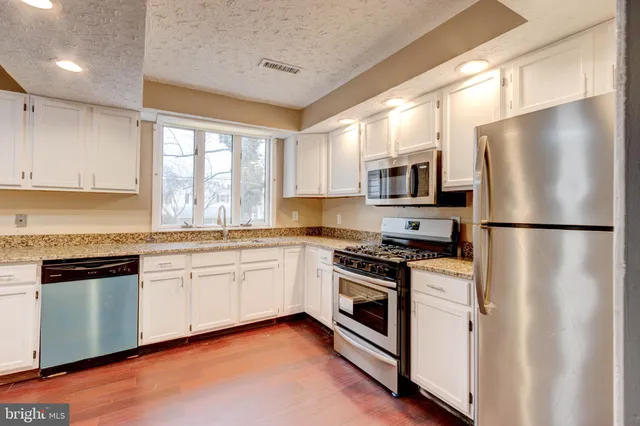 a kitchen with granite countertop white cabinets and stainless steel appliances