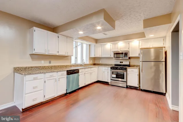 a kitchen with stainless steel appliances kitchen island granite countertop a refrigerator and a stove top oven