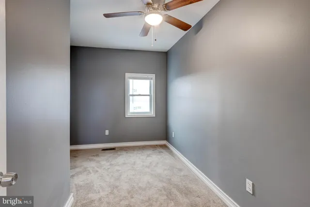 an empty room with a ceiling fan and carpet