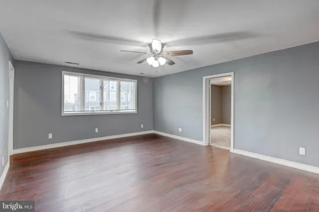 a view of an empty room with window and wooden floor