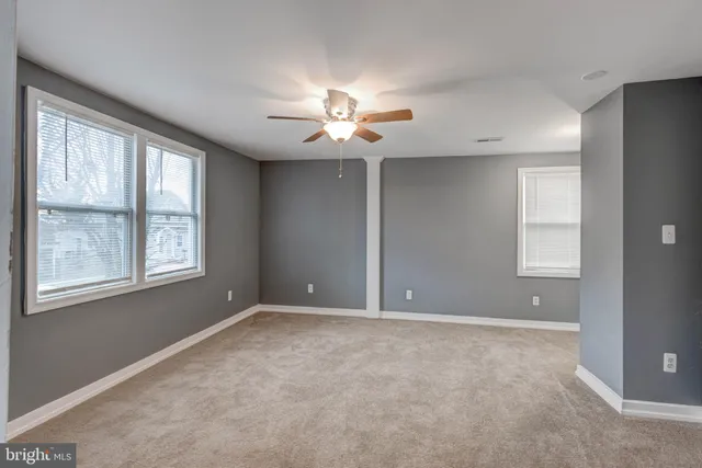 a view of an empty room with window and chandelier fan