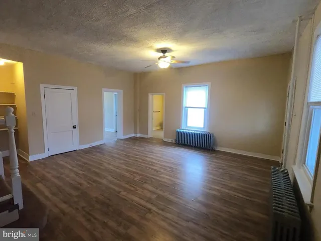 a view of empty room with window and wooden floor