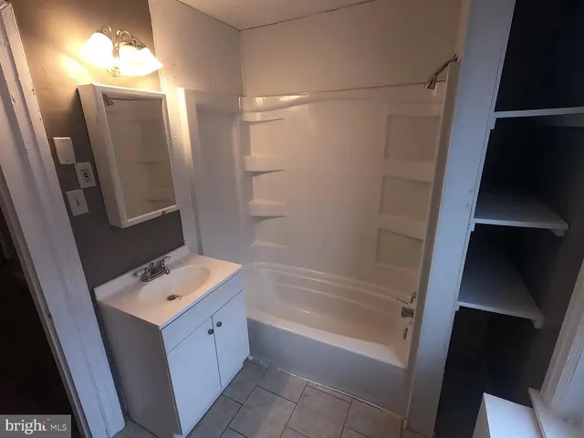 a bathroom with a tub sink and mirror