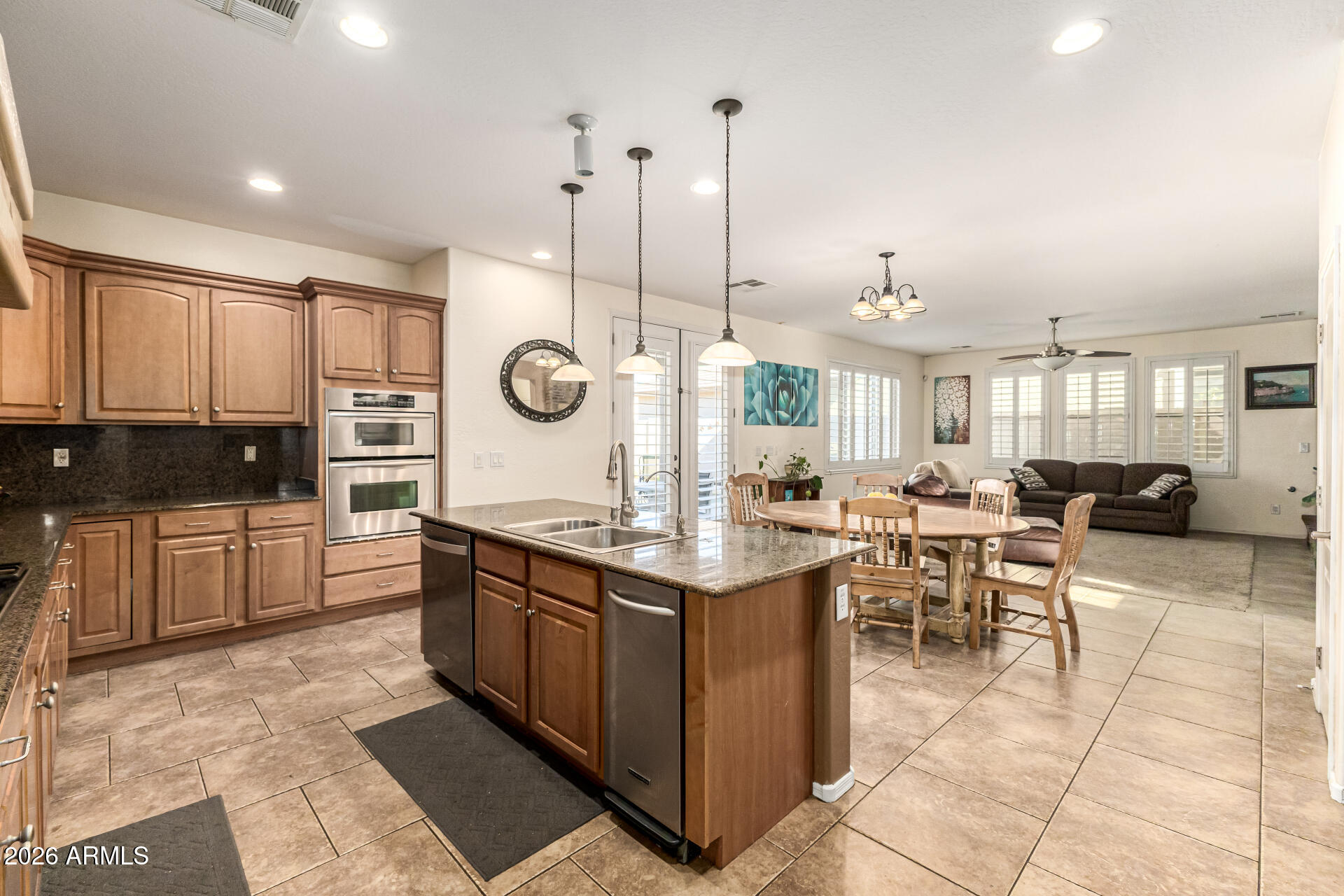 2858 East Shannon Street Gilbert, AZ 85295 - Photo 11 of 35 a kitchen with stainless steel appliances kitchen island granite countertop a stove a sink a oven a dining table and chairs with white cabinets