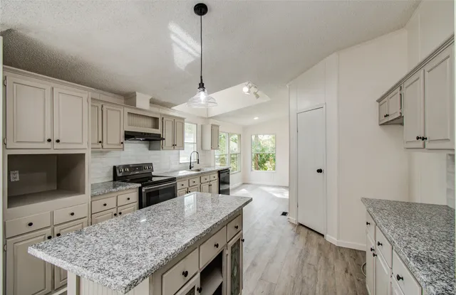 a kitchen with stainless steel appliances granite countertop a stove refrigerator sink and cabinets