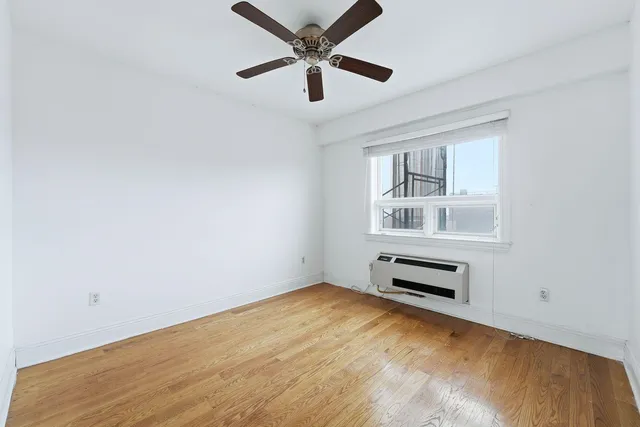an empty room with ceiling fan and windows