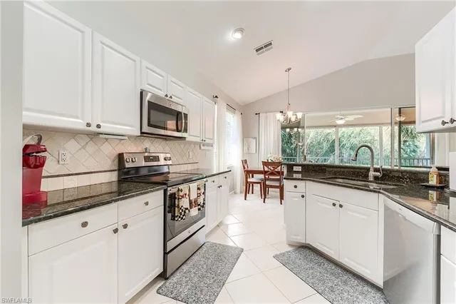 a kitchen with granite countertop a sink and white cabinets