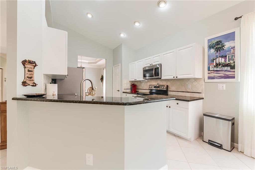 23166 Rosedale Drive, Unit 201 Estero, FL 34135 - Photo 6 of 40 a kitchen with granite countertop white cabinets and stainless steel appliances