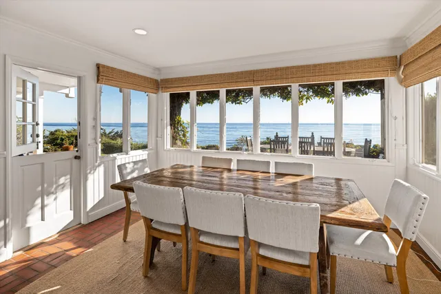a dining room with furniture large windows and wooden floor