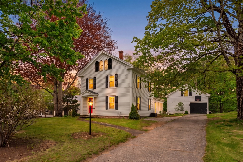 a view of a white house with a yard and large tree